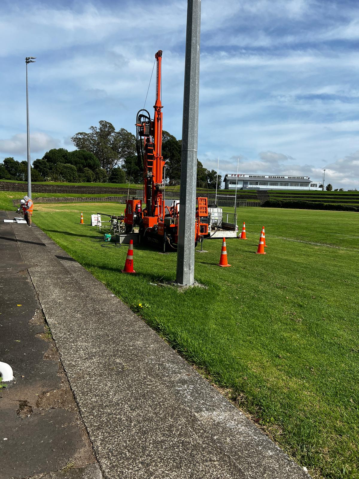 Track-mounted geotechnical drill rig carrying out a borehole investigation with traffic cones and site set-up in place
