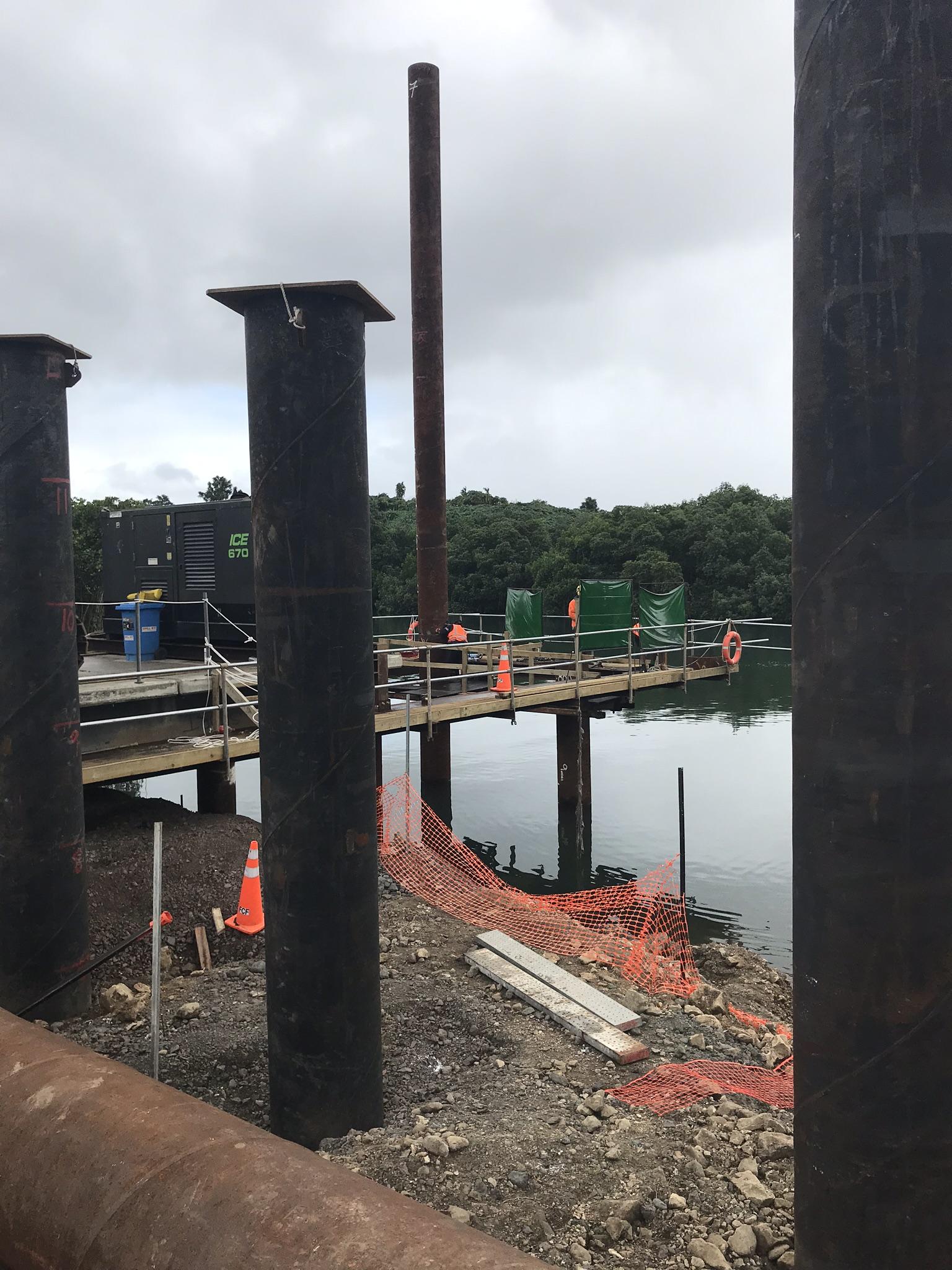 Steel tubular piles and a temporary working jetty over tidal water at a marine construction site